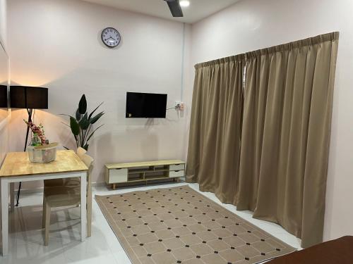 a living room with a table and a tv and a curtain at Paktam Ruduwe Homestay in Marang