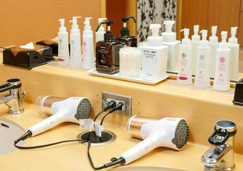 a bathroom counter with hair dryers and bottles of soap at APA Hotel Osaka Temma in Osaka