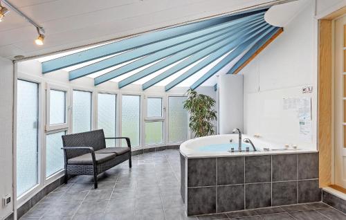 bagno con vasca, sedia e finestre di Beautiful Home In Otterup With Sauna a Otterup