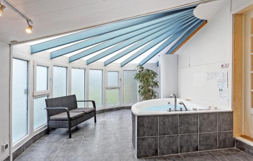 baño con bañera, silla y ventanas en Awesome Home In Otterup With 4 Bedrooms, Sauna And Wifi, en Otterup