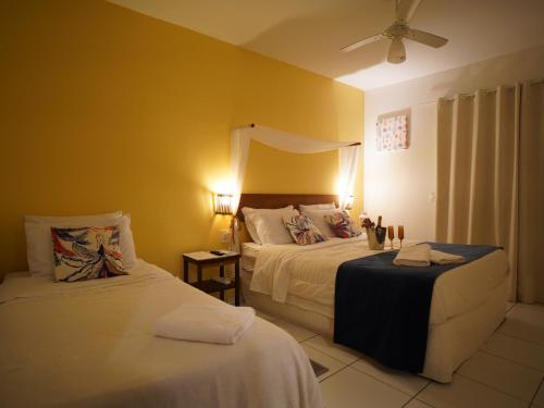 a bedroom with two beds and a ceiling fan at Hotel Liberdade Búzios in Búzios