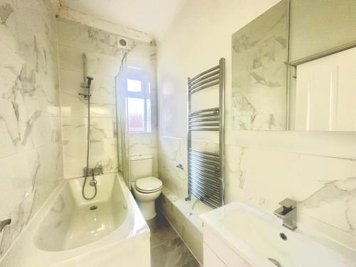ein weißes Badezimmer mit einem WC, einer Badewanne und einem Waschbecken in der Unterkunft The Euston Guest House-64 in London