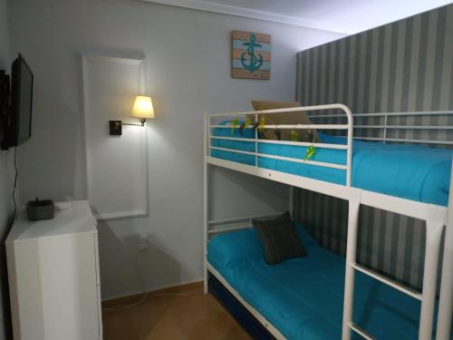 a bedroom with two bunk beds with blue sheets at Luz de la Bahía - Bahía Sur San Fernando Cádiz in San Fernando