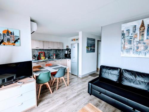 ein Wohnzimmer mit einer schwarzen Couch und einer Küche in der Unterkunft T2 climatisé vue sur mer, WIFI, piscine et parking in Sète
