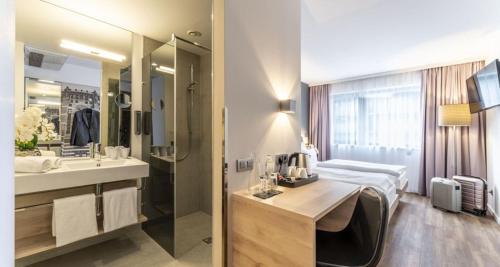a hotel room with a bed and a bathroom at PLAZA INN Wien Gasometer in Vienna