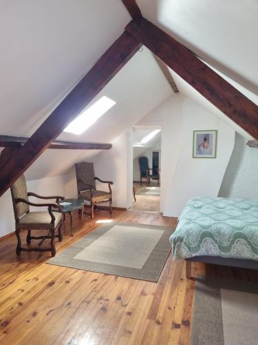 - une chambre mansardée avec un lit et des chaises dans l'établissement Domaine Le Beau Lavault, à Thil-sur-Arroux