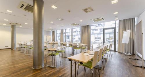 a dining room with tables and chairs and windows at PLAZA INN Wien Gasometer in Vienna