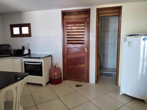 a kitchen with a white refrigerator and a door at Chalé na praia de Carapibus in Conde