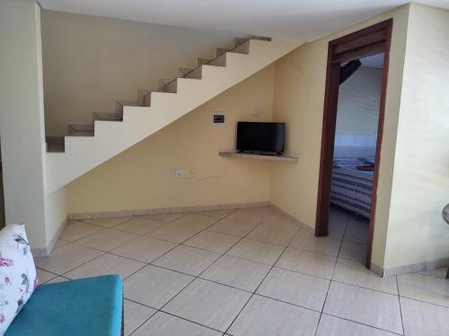 a living room with a staircase and a television at Chalé na praia de Carapibus in Conde