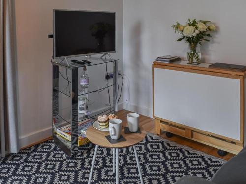 a living room with a flat screen tv and a table with cups at Picturesque Cabin in Cornwall in Camborne