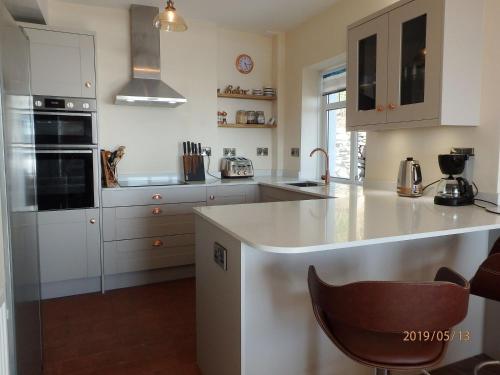 cocina con armarios blancos y encimera en Bryn Mair in Barmouth, en Barmouth
