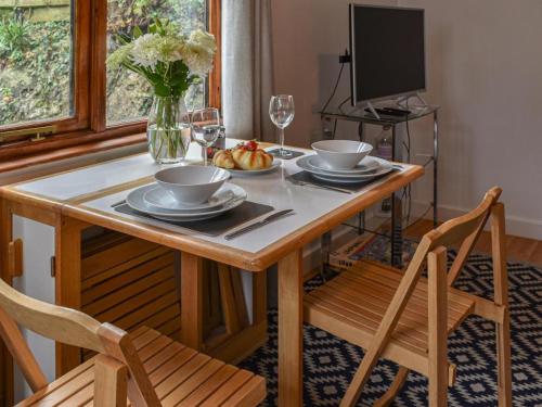 a dining room table with two chairs and a television at Picturesque Cabin in Cornwall in Camborne