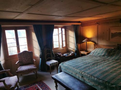 una camera con letto, sedia e finestre di Nouveau à Rougemont: Appartement dans Chalet 1830 a Rougemont