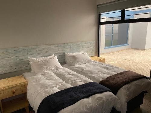 ein großes Bett in einem Zimmer mit einem großen Fenster in der Unterkunft DieStrandwolf Sea View Self Catering in Henties Bay