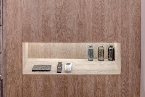 a shelf with three vases and a remote control at CHANTTAL Luxury - BOUTIQUE in Bucharest