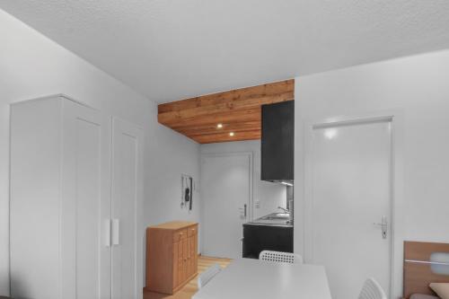 a kitchen with white walls and a wooden ceiling at Studio cosy au centre de Crans-Montana in Crans-Montana