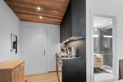 eine Küche mit weißen Wänden und einer Holzdecke in der Unterkunft Studio cosy au centre de Crans-Montana in Crans-Montana