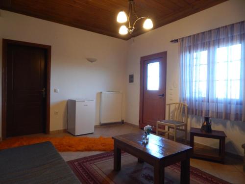 a living room with a table and a refrigerator at Παραδοσιακός Ξενώνας Αετορράχης - Aetorrachi's Traditional Guesthouse in Aëtorráchi