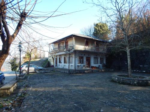 an old house with a car parked in front of it at Παραδοσιακός Ξενώνας Αετορράχης - Aetorrachi's Traditional Guesthouse in Aëtorráchi