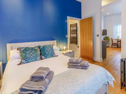 ein blaues Schlafzimmer mit einem großen Bett mit Handtüchern darauf in der Unterkunft Luxury studio above the stunning Tenby Harbour in Tenby