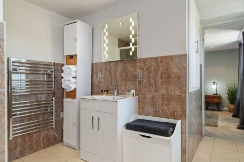 Baño blanco con lavabo y espejo en Luxury three bedroom coastal cottage, en Cardigan