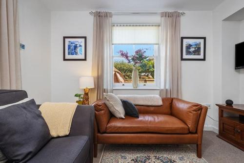 a living room with a brown leather couch and a window at Luxury three bedroom coastal cottage in Cardigan