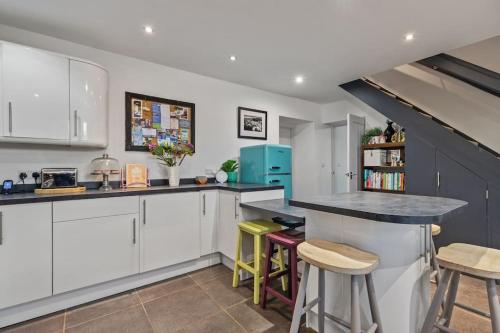 a kitchen with white cabinets and a counter with stools at Luxury three bedroom coastal cottage in Cardigan