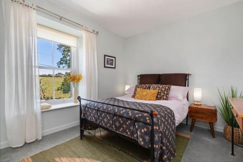 1 dormitorio con cama y ventana en Luxury three bedroom coastal cottage, en Cardigan