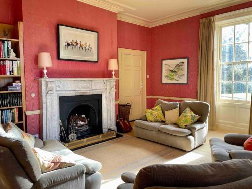 a living room with red walls and a fireplace at Marlacoo House Luxury Georgian home in Portadown