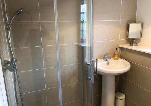 La salle de bains est pourvue d'une douche et d'un lavabo. dans l'établissement Jasmine Cottage, sleeps 6 near Elie, with garden, à Fife