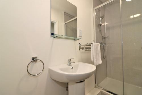 a white bathroom with a sink and a shower at Signature - No 5 Bonnet Apartments in Lanark
