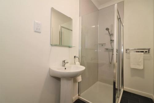a white bathroom with a sink and a shower at Signature - No 1 Bonnet Apartments in Lanark