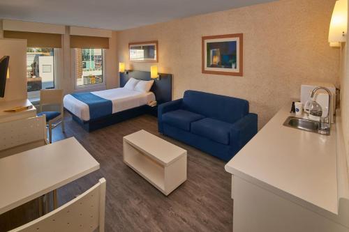 a hotel room with a bed and a blue couch at City Express by Marriott Aguascalientes Sur in Aguascalientes