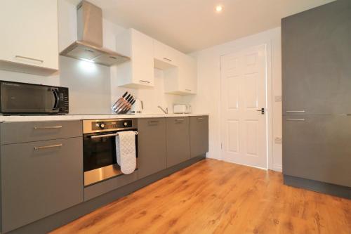 a kitchen with stainless steel appliances and a wooden floor at Signature - No 7 Bonnet Apartments in Lanark