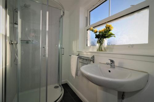 baño con lavabo y jarrón de flores en Signature - No 7 Bonnet Apartments en Lanark