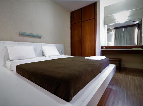 ein Schlafzimmer mit einem großen Bett mit einer braunen Decke in der Unterkunft Grande Hotel Universo Palace in Uberlândia