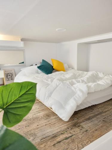 a bedroom with a large bed with white sheets at Yellow House - Duplex, Night view, White modern interior in Bucheon