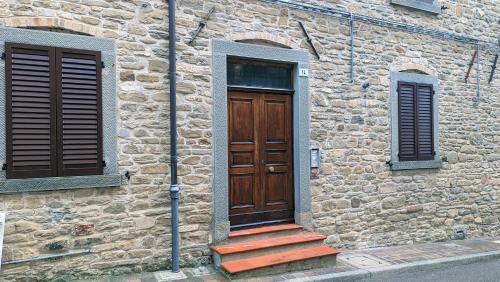 a stone building with a wooden door and stairs at Lo Struzzo in Bagno di Romagna