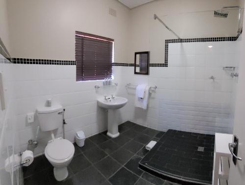 a white bathroom with a toilet and a sink at Harewood Lodge in East London