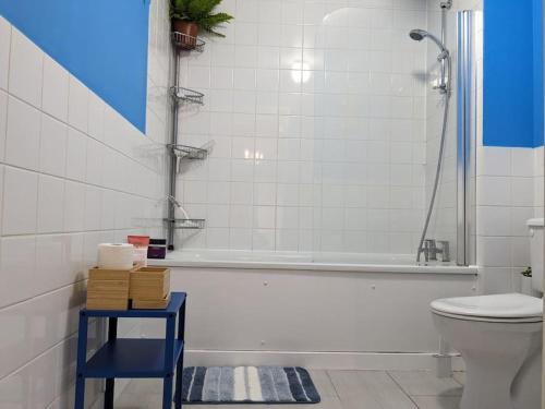 baño con bañera, aseo y taburete azul en Cheersome en Londres