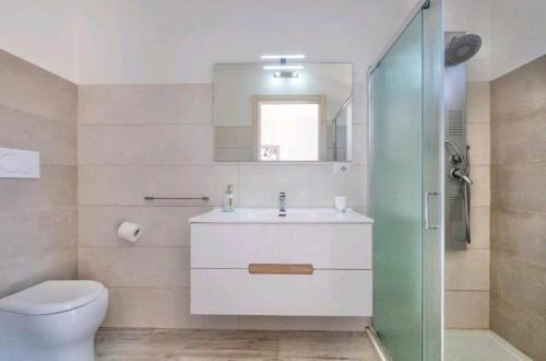 Un baño con lavabo, inodoro y espejo. en Villa Perla Salentina luxury, en Taviano