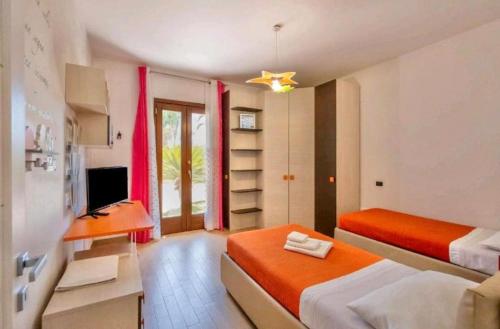Un dormitorio con dos camas y un escritorio y un televisor. en Villa Perla Salentina luxury, en Taviano
