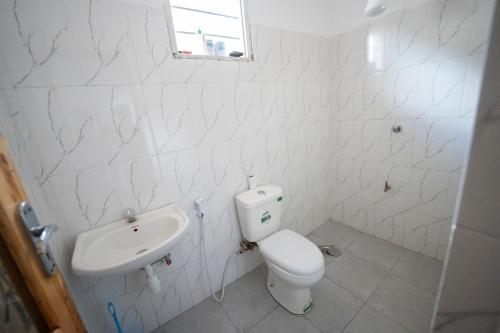 a white bathroom with a toilet and a sink at Mkoani Homestay in Moshi