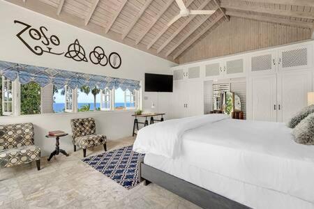 sypialnia z dużym białym łóżkiem i telewizorem w obiekcie Hospitality Expert Zeppelin - Tour Pool Bar Beach w mieście Montego Bay
