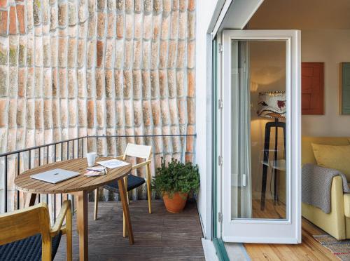 a dining room with a table and a balcony at Story Studio Coimbra Centro - Culture in Coimbra