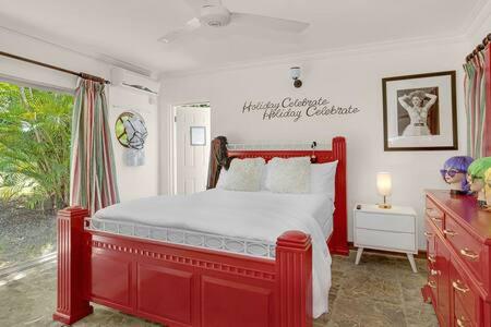 a bedroom with a red bed and a window at Hospitality Expert Madonna Tour Pool Bar Beach in Montego Bay