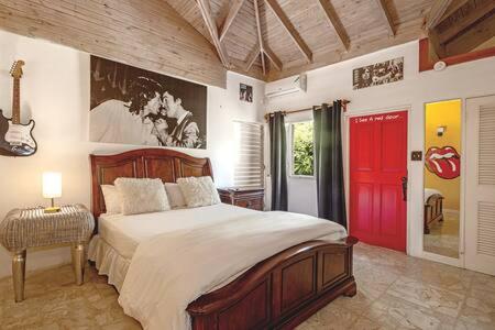 a bedroom with a large bed and a red door at Hospitality Expert Jagger - Tour Pool Bar Beach in Montego Bay