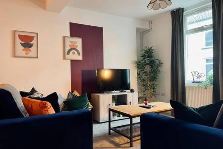 uma sala de estar com dois sofás e uma televisão em Taff Valley Cottage by StayStaycations em Merthyr Tydfil