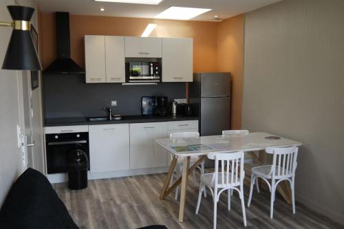 une cuisine avec une table, des chaises et un réfrigérateur dans l'établissement Appartement 4/6 pers accès plage direct : Batz, à La Bernerie-en-Retz