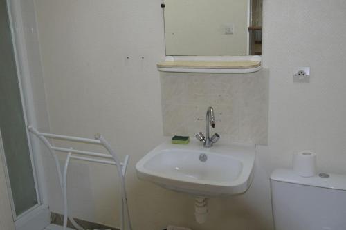 une salle de bain blanche avec un lavabo et un miroir dans l'établissement Appartement 4/6 pers accès plage direct : Batz, à La Bernerie-en-Retz